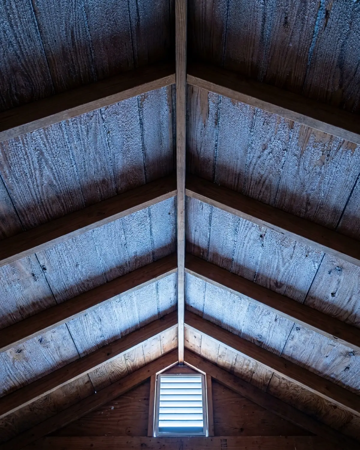Frost on the underside of attic roof sheathing between wood rafters